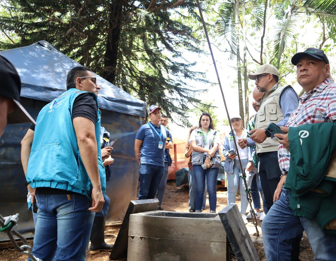 La imagen muestra a un grupo de personas reunidas en un entorno natural, probablemente en un sitio de trabajo de recuperación ambiental. Visten ropa cómoda y algunos llevan chalecos identificativos. 